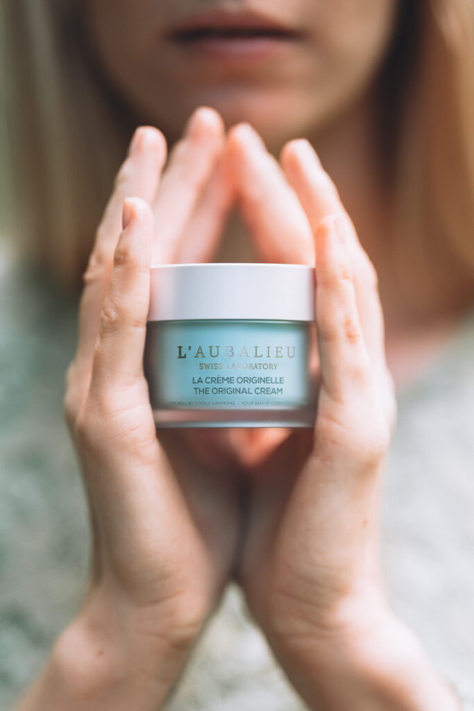 Deux mains qui tiennent un produit cosmétique de l'Aubalieu